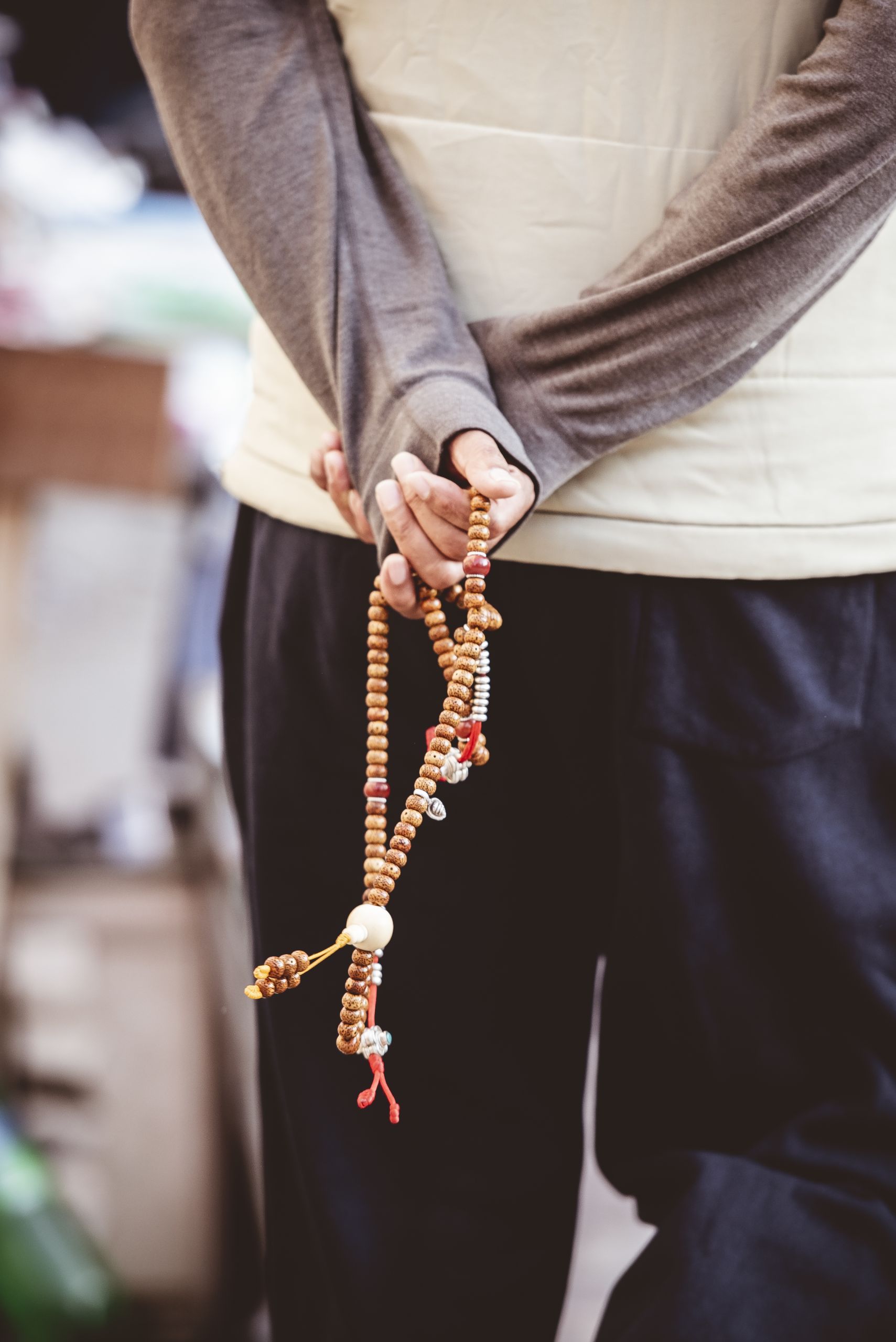 Vertical closeup shot of a male holding a chain of beads behind the back